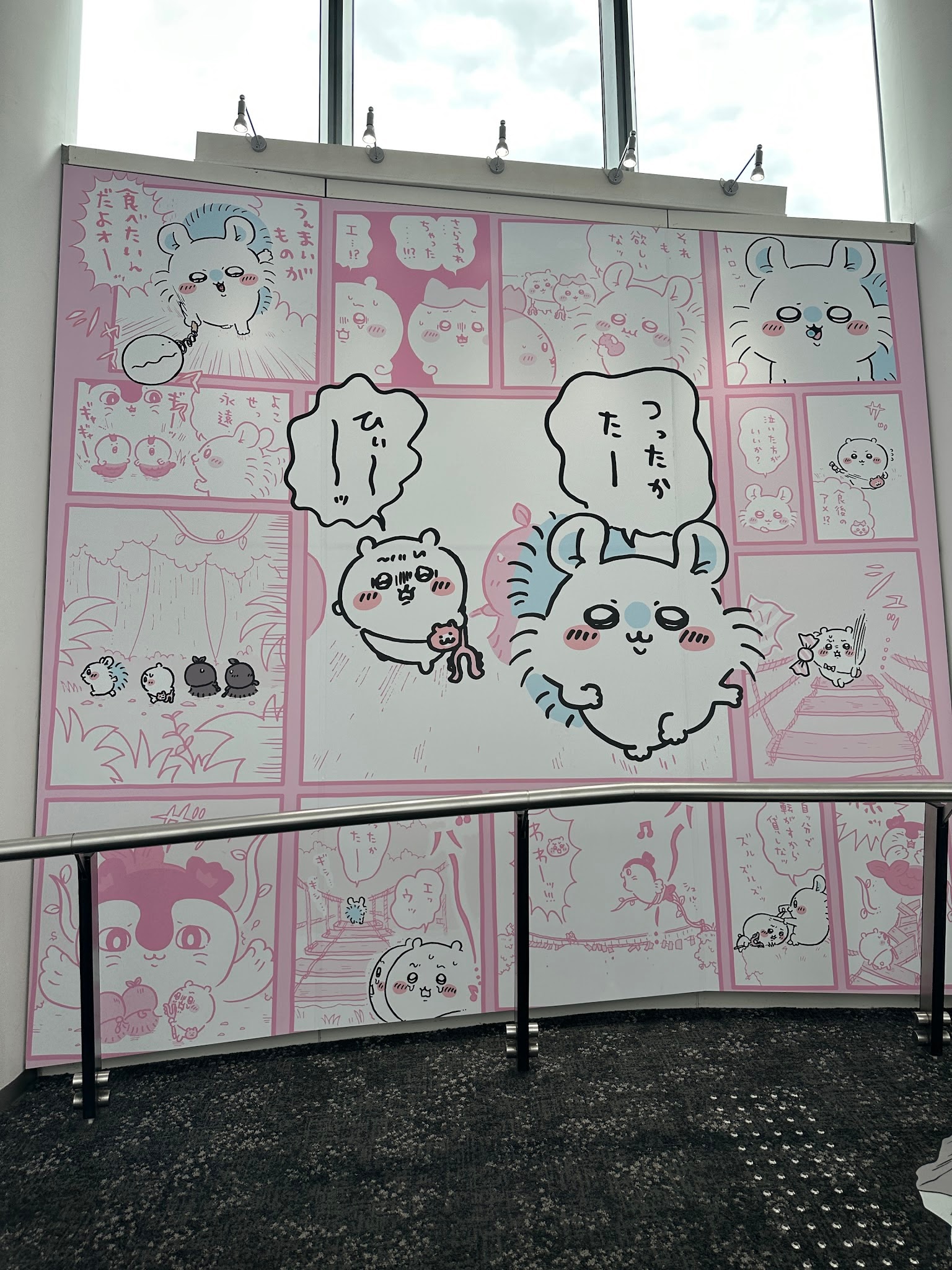 ピンク色の漫画シーンを描いた壁面展示